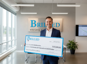Business owner holding rebate check with Brilled Lighting logo in a brightly lit office